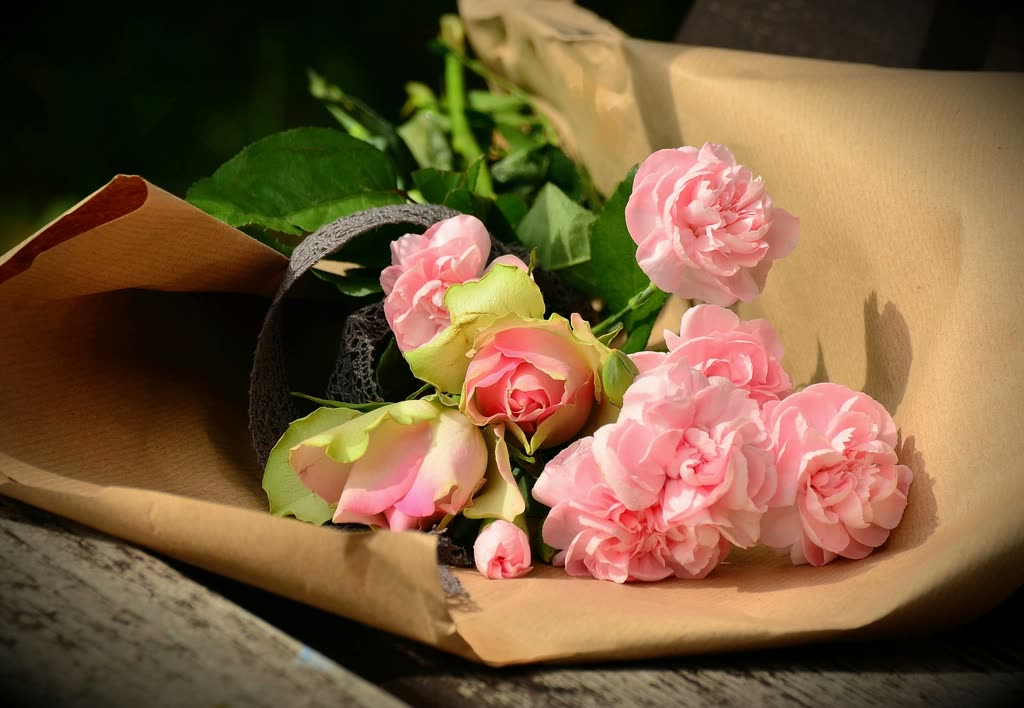 Pink roses and ruffled pink flowers in a brown paper wrap